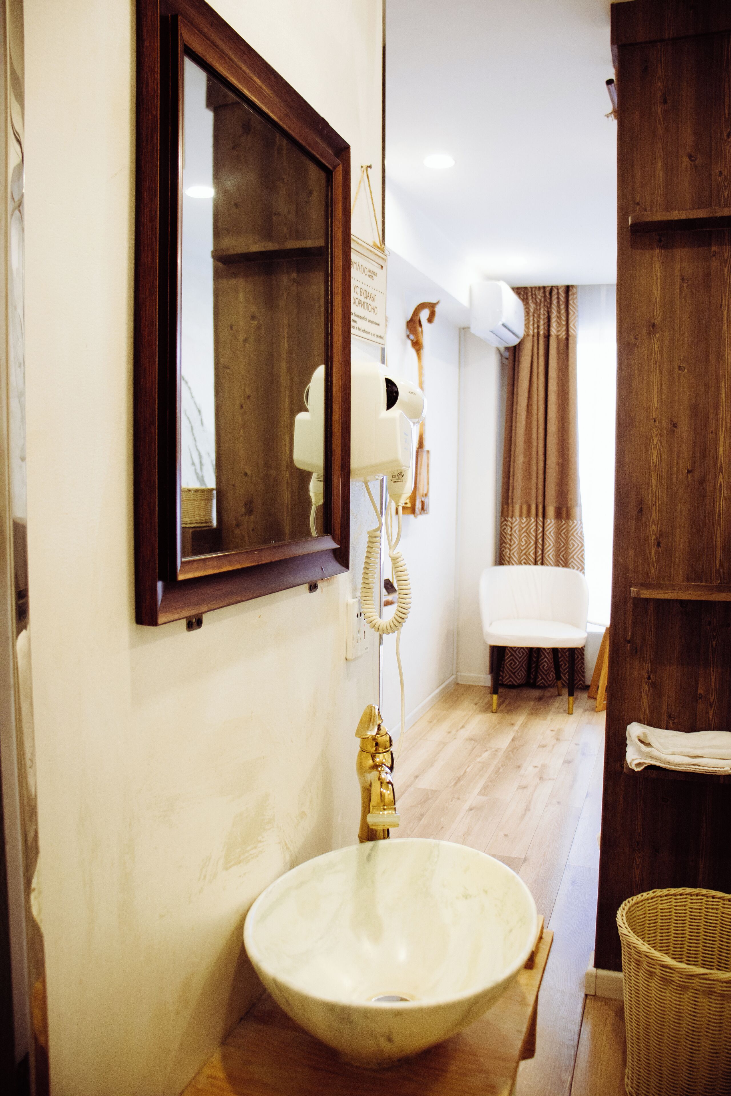 A bathroom with a wooden vanity, a white sink, a mirror, and a towel rack.