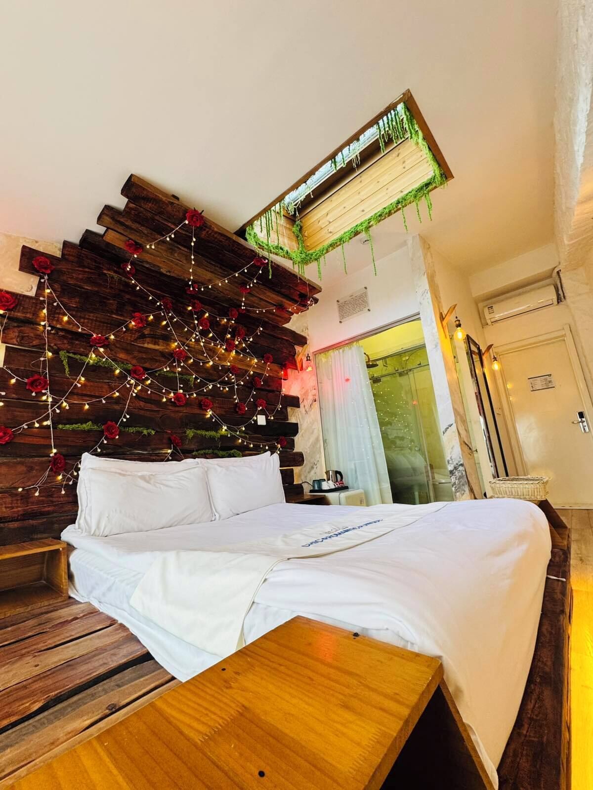 Ein Bett mit weißer Bettwäsche, einem Holz-Kopfteil und einer Lichterkette.