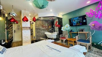 A hotel room with a bed, a shower area, a TV, and a neon sign.