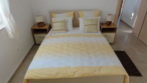 A neatly made bed with a striped bedspread, two bedside tables with lamps, and a rug on the floor. - Apartments Cubela Beautiful Garden (Trogir)