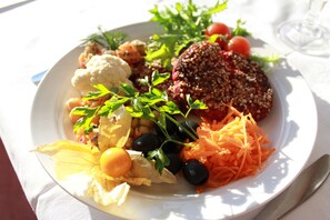 A plate of food with various vegetables and a glass of water. - Liljeholmen Herrgård (Rimforsa)