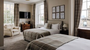 A hotel room with two beds, a sofa, a TV, and a window with curtains. - The Dunvegan Hotel (St. Andrews)
