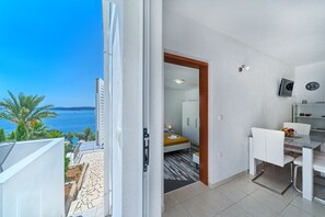 A modern room with a bed, a dining area, and a view of the sea. - Apartment Lozovina - Panoramic Sea View (Seget)