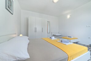 A modern hotel room with a large bed, a small desk, and a mirror. - Apartment Lozovina - Panoramic Sea View (Seget)