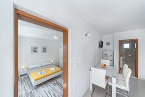 Quarto moderno com uma cama, mesa de cabeceira e um pequeno espaço de trabalho com uma cadeira.