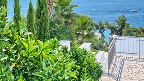 A coastal view with a clear blue sky, palm trees, and a body of water. - Apartment Lozovina - Panoramic Sea View (Seget)