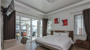 Une chambre d’hôtel moderne dotée d’un grand lit, d’un bureau et d’une porte-fenêtre coulissante donnant sur un espace extérieur aménagé pour se détendre.