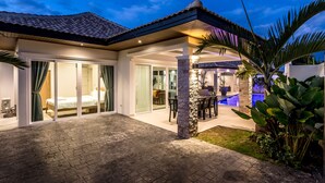 Una casa moderna con un patio, piscina y un área de estar techada al aire libre.