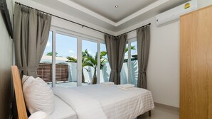 Un dormitorio moderno con una cama grande, un armario de madera y vistas a palmeras a través de las ventanas.