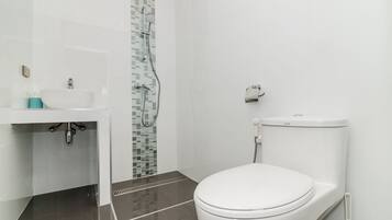 A modern bathroom with a white sink, a toilet, and a shower area.
