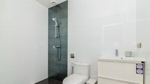Un baño moderno con ducha, inodoro y tocador.