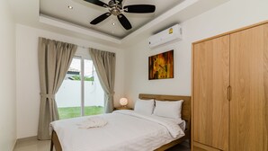 A bedroom with a bed, a wardrobe, a ceiling fan, and a window with curtains. - Orchid Paradise Homes OPV313 (Hua Hin)