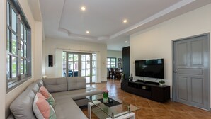Un salón amplio con un sofá grande, una mesa de centro de cristal y un televisor de pantalla plana.