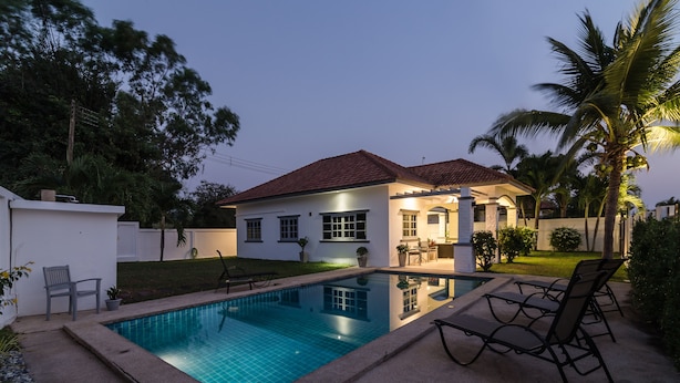 Propiedad residencial con piscina, zona de estar exterior y jardín cuidado.