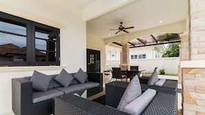 A modern outdoor seating area with a sofa and chairs, a ceiling fan, and a view of the surrounding neighborhood. - Orchid Paradise Homes OPV22 (Hua Hin)