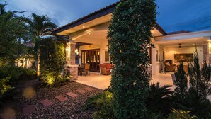 A house with a covered patio, outdoor seating, and a garden with a variety of plants.