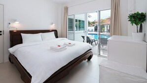 A modern hotel room with a large bed, a balcony with a pool view, and a white color scheme. - Orchid Paradise Homes OPV02 (Hua Hin)