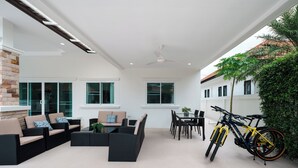 A spacious outdoor area with a dining table, chairs, and a yellow bicycle. - Orchid Paradise Homes OPV02 (Hua Hin)