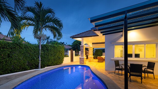 Une maison moderne dotée d’une piscine, de mobilier de jardin et d’un espace extérieur couvert.