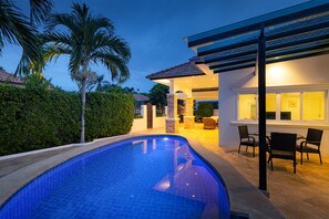 A modern house with a swimming pool, patio furniture, and a covered outdoor area.