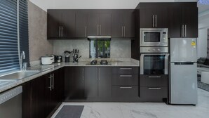 A modern kitchen with dark cabinets, stainless steel appliances, and a granite countertop.