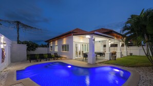 A modern house with a swimming pool, outdoor seating, and a covered patio area.