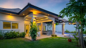 Ein modernes Haus mit überdachter Terrasse, Swimmingpool und gepflegtem Garten.