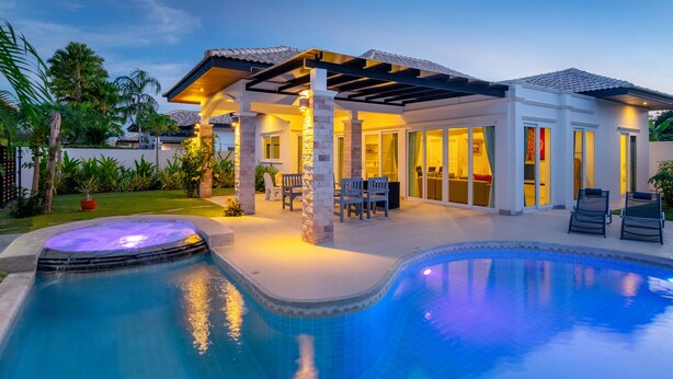 Ein modernes Haus mit Swimmingpool, Sitzgelegenheiten im Freien und einer überdachten Terrasse.