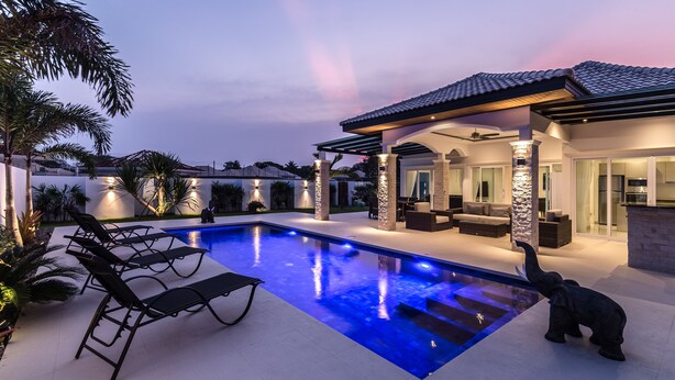 A modern house with a swimming pool, outdoor seating, and a stone pillar. - Orchid Paradise Homes OPV401 (Hua Hin)