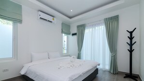 A modern hotel room with a large bed, air conditioning unit, and a coat rack. - Orchid Paradise Homes OPV301 (Hua Hin)