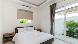 A modern bedroom with a large bed, a window, and a sliding glass door to a balcony. - Orchid Paradise Homes OPV404 (Hua Hin)