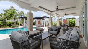 An outdoor patio with a pool, wicker furniture, and a covered area with a ceiling fan. - Orchid Paradise Homes OPV404 (Hua Hin)