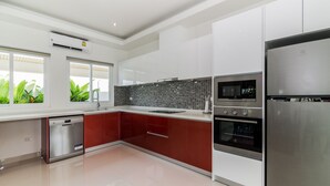 A modern kitchen with stainless steel appliances, a dishwasher, and a tiled backsplash. - Orchid Paradise Homes OPV404 (Hua Hin)