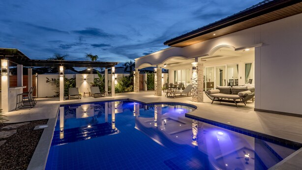 A swimming pool with a sunken seating area, surrounded by a covered patio with outdoor furniture. - Orchid Paradise Homes OPV404 (Hua Hin)