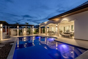 Une piscine dotée d’un espace salon aménagé en contrebas, entourée d’une terrasse couverte avec des meubles d’extérieur.