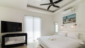 A modern hotel room with a large bed, a flat-screen TV, a ceiling fan, and a painting on the wall. - Orchid Paradise Homes OPV210 (Hua Hin)