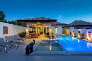 A modern house with a swimming pool, outdoor seating, and a well-lit patio area. - Orchid Paradise Homes OPV211 (Hua Hin)