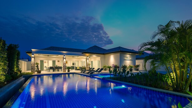 A modern house with a swimming pool, outdoor seating, and lush greenery. - Orchid Paradise Homes OPV219 (Hua Hin)
