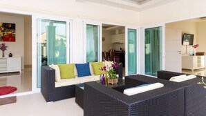 A modern living room with a sofa, coffee table, and wicker furniture. - Orchid Paradise Homes OPV219 (Hua Hin)