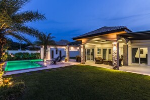 Une maison moderne dotée d’une piscine, d’un espace salon extérieur et d’un patio couvert.