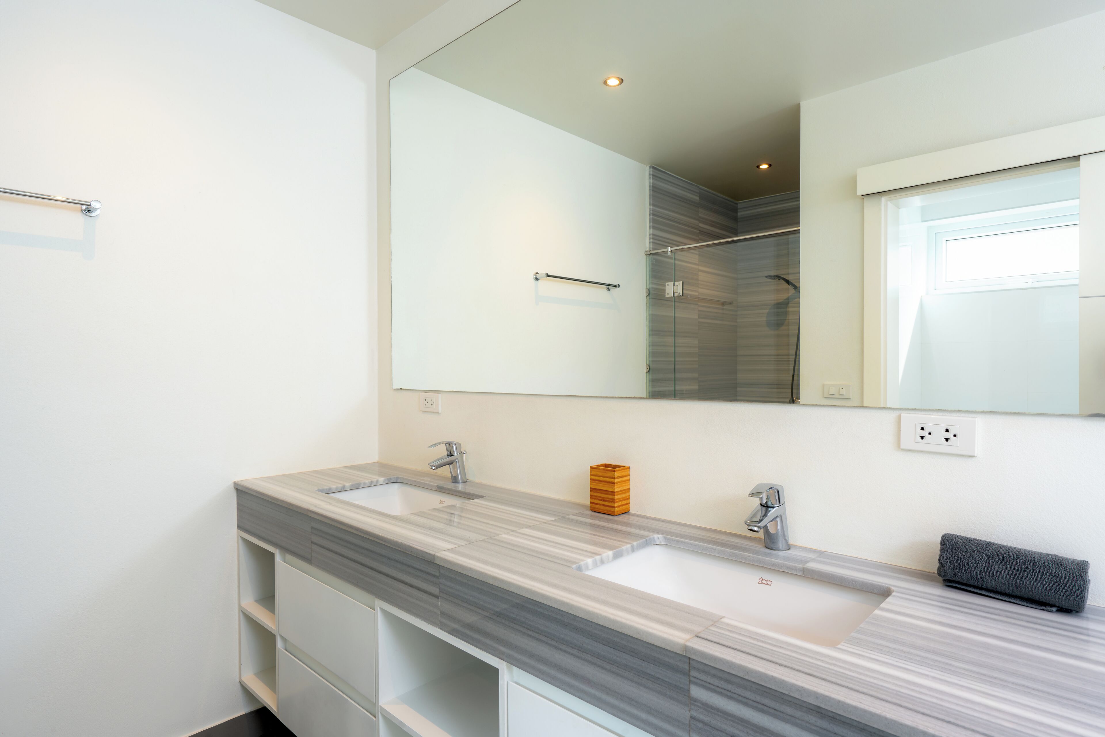 Een moderne badkamer met een grote spiegel, twee wastafels en een douche.