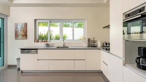 Une cuisine moderne équipée d’un lave-vaisselle, d’un évier et d’une fenêtre donnant sur un espace verdoyant.