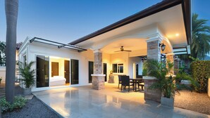 A modern house with a spacious patio, a dining area, and a bedroom with sliding glass doors.