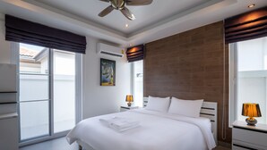 A modern hotel room with a large bed, a ceiling fan, and a view of the outside. - Orchid Paradise Homes OPV213 (Hua Hin)