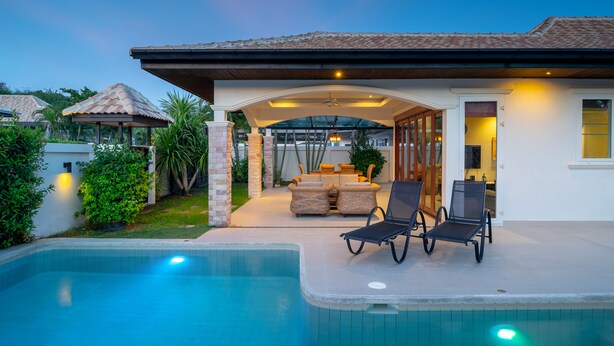 A poolside area with lounge chairs, a covered patio, and a view of the house. - Orchid Paradise Homes OPV213 (Hua Hin)