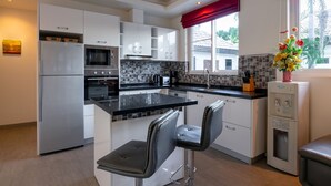 A modern kitchen with white cabinets, a stainless steel refrigerator, a microwave, and a water dispenser. - Orchid Paradise Homes OPV213 (Hua Hin)