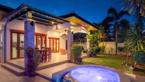 A modern house with a covered patio, a swimming pool, and a well-maintained garden.
