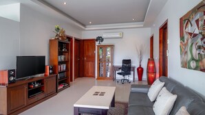 A living room with a TV, wooden cabinets, a sofa, and a coffee table.