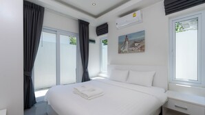 A modern hotel room with a large bed, a bedside table, and a window with curtains. - Orchid Paradise Homes OPV315 (Hua Hin)