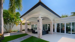 A covered patio area with a white roof, stone pillars, and a seating area with sofas and a table. - Orchid Paradise Homes OPV315 (Hua Hin)